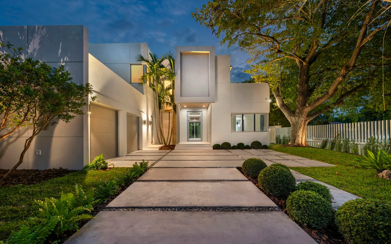 Modern home with an illuminated front walkway at dusk